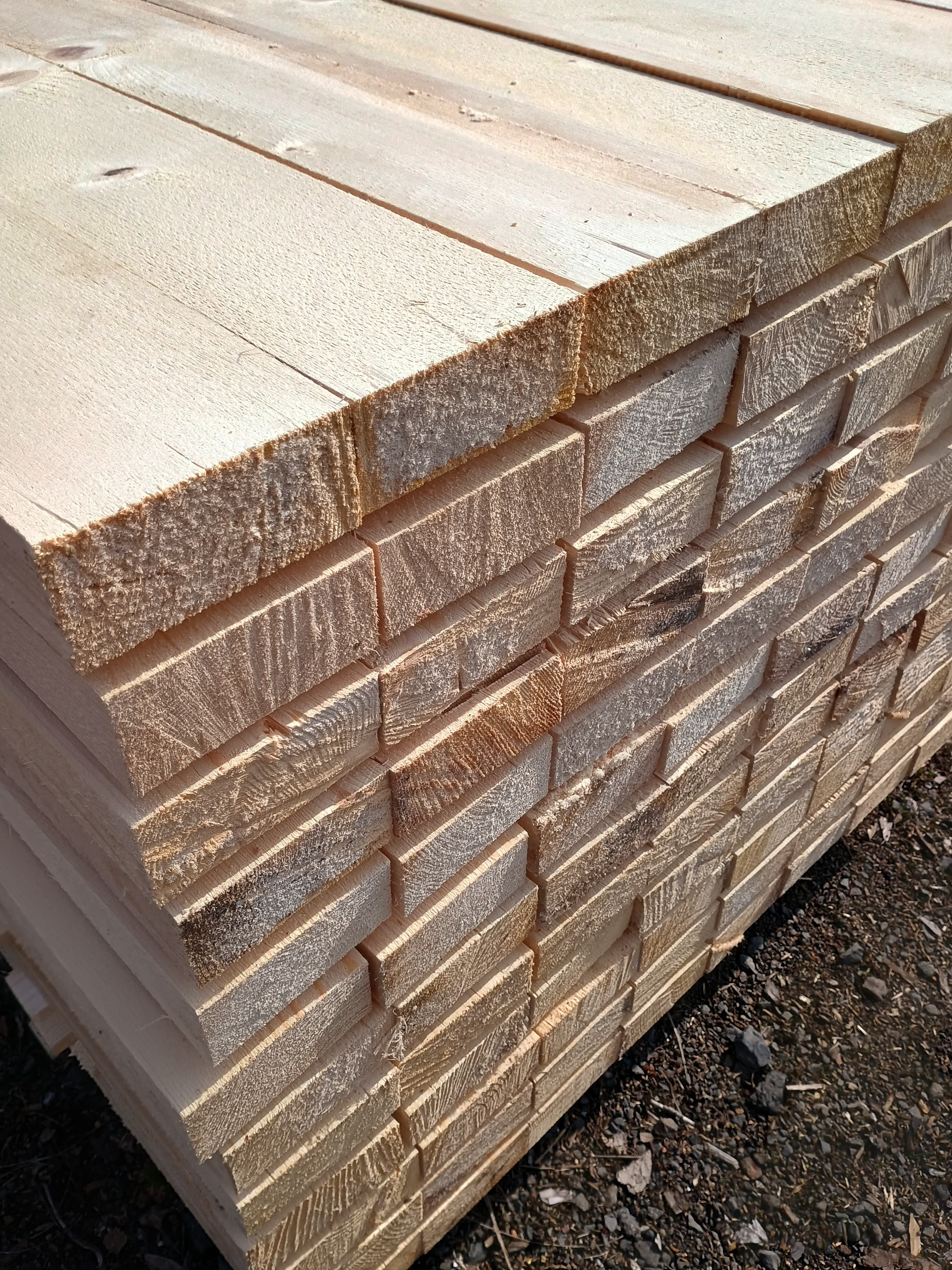 Stack of light-colored wooden planks with deep, parallel notches cut into the top surface.