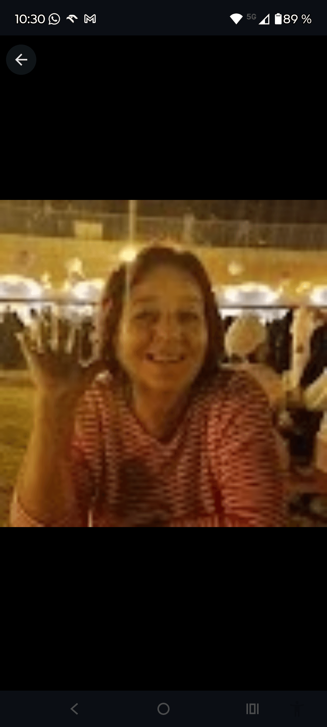 Smiling woman with reddish hair wearing a red striped shirt waves her hand.